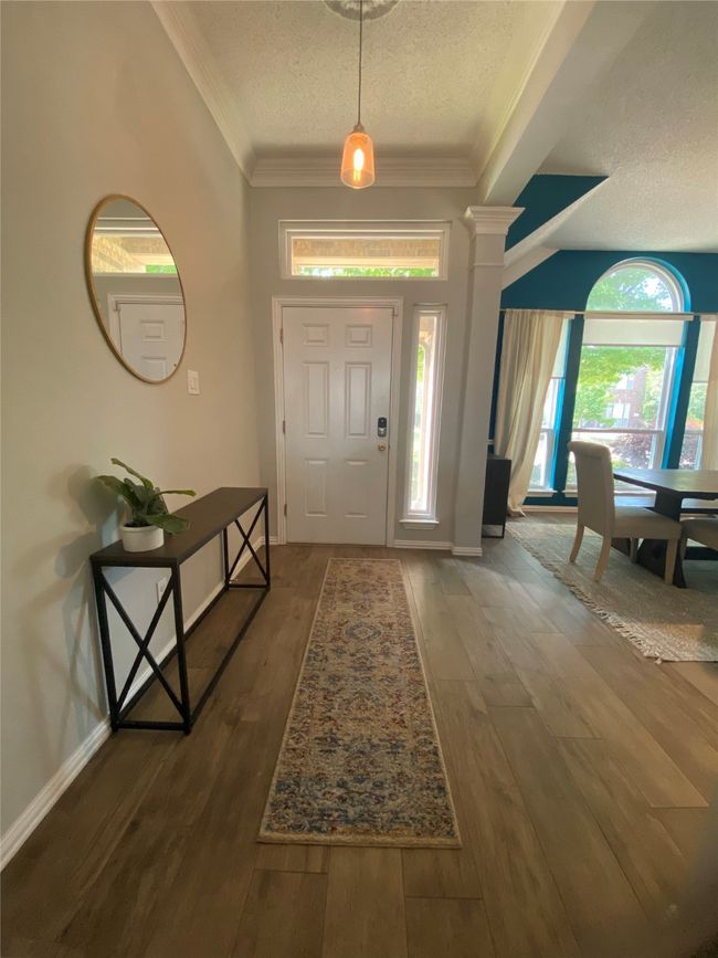 Foyer featuring a textured ceiling, wood finished floors, baseboards, and ornamental molding | Image 4