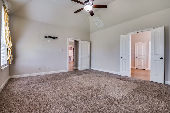 Unfurnished bedroom with carpet floors, high vaulted ceiling, and ceiling fan | Image 14