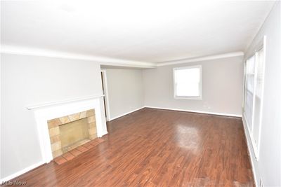 Unfurnished living room featuring a tiled fireplace and dark hardwood / wood-style floors | Image 2