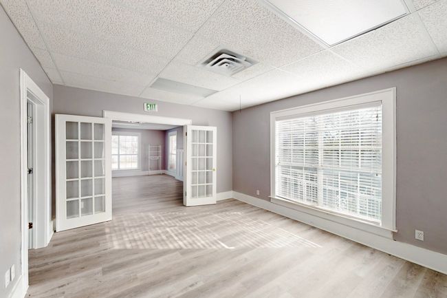 Empty room with light wood-type flooring, a paneled ceiling, and french doors | Image 13