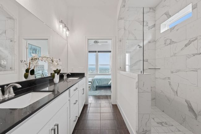 Featuring a stunning oversized walk-in shower with frameless glass splash guard and designer tile surround. | Image 22