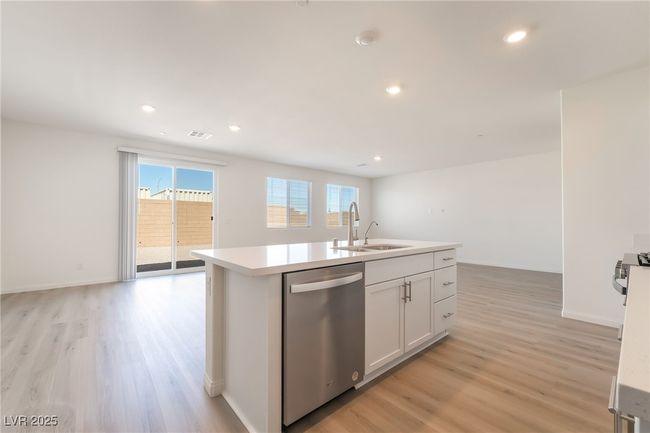 Kitchen with stainless steel dishwasher, light wood-style floors, light countertops, a center island with sink, and recessed lighting | Image 12