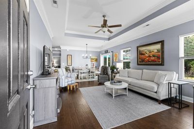 Living room featuring ceiling fan with notable chandelier, crown molding, dark hardwood / wood-style flooring, and a wealth of natural light | Image 3