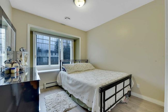 Bedroom with baseboard heating, light wood-type flooring, and baseboards | Image 34