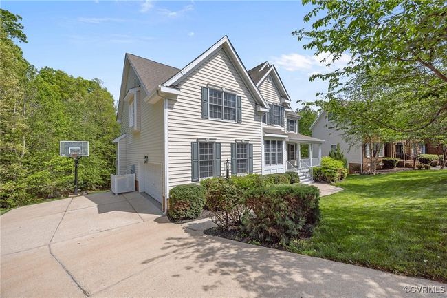 View of side of property featuring central AC unit, concrete driveway, a yard, and a garage | Image 4