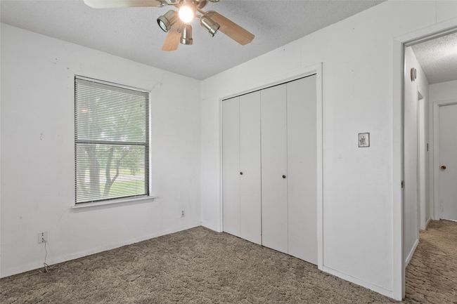 Unfurnished bedroom featuring carpet floors, a textured ceiling, a closet, and ceiling fan | Image 19