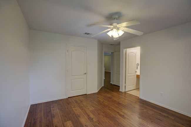 Unfurnished bedroom featuring baseboards, wood finished floors, ceiling fan, and connected bathroom | Image 26