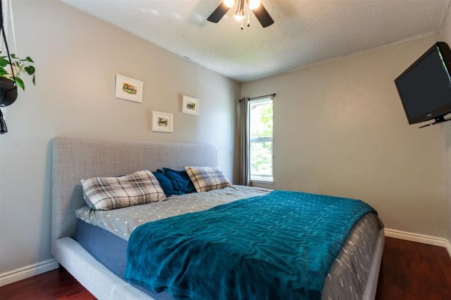 Bedroom featuring wood finished floors, a ceiling fan, and a textured ceiling | Image 18