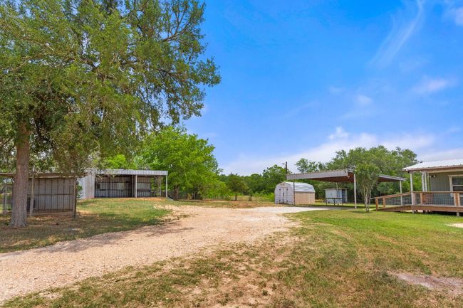 View of grassy yard featuring dirt driveway and a carport | Image 15