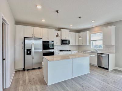 Expansive, timeless, white kitchen with refrigerator, double ovens, gas cooktop, microwave vented to outside, and soft close doors and drawers. | Image 3