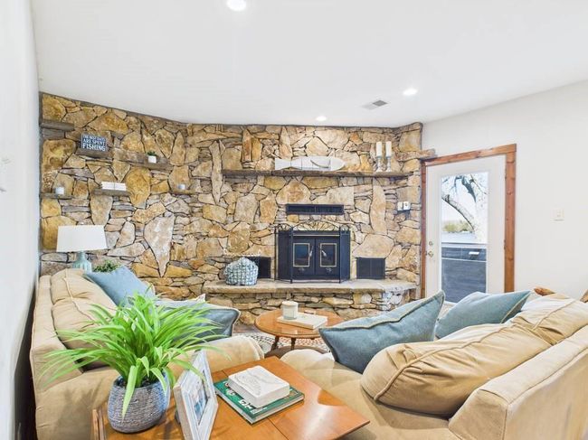 Lower level family area featuring recessed lighting, a fireplace, and visible vents with door outside leading to hot tub | Image 51