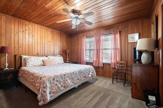 Bedroom featuring wood ceiling, wooden walls, carpet, and ceiling fan | Image 9