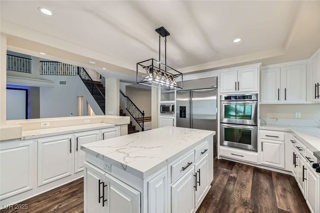 Kitchen with built in appliances, a center island, a chandelier, dark wood-type flooring, and recessed lighting | Image 13