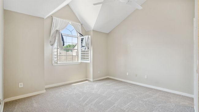 Spare room featuring a ceiling fan, carpet, baseboards, and lofted ceiling | Image 17