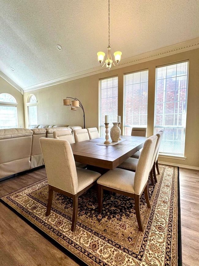 Dining space featuring ornamental molding, a chandelier, a textured ceiling, vaulted ceiling, and wood finished floors | Image 5