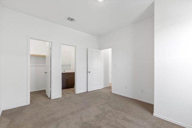 Unfurnished bedroom with light carpet, a walk in closet, a closet, and connected bathroom | Image 11