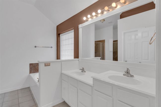Bathroom with double vanity, a bath, a shower with door, tile patterned floors, and vaulted ceiling | Image 22
