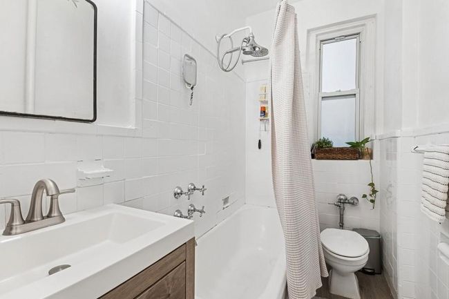 Bathroom with toilet, tile walls, vanity, and shower / bath combo | Image 10