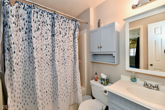 bathroom featuring shower / bathtub combination with curtain, a textured ceiling, vanity, and toilet | Image 9