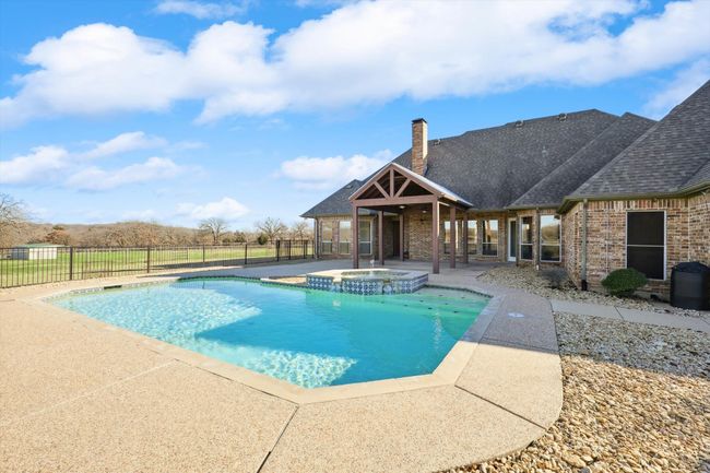 View of swimming pool featuring a patio area and a pool with connected hot tub | Image 24