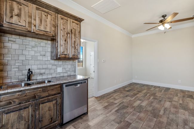 Kitchen with stainless steel dishwasher, a sink, a ceiling fan, dark wood finished floors, and decorative backsplash | Image 29