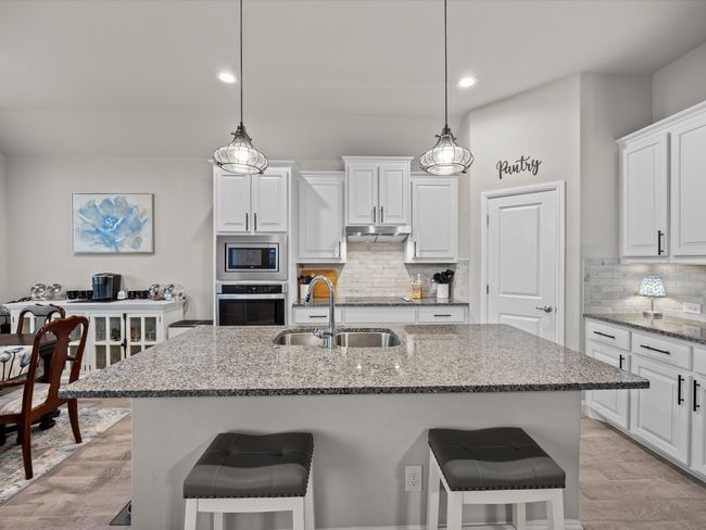 Kitchen featuring appliances with stainless steel finishes, under cabinet range hood, a breakfast bar, stone counters, and recessed lighting | Image 8
