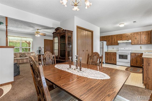 Dining space featuring a textured ceiling, a chandelier, and ceiling fan | Image 15
