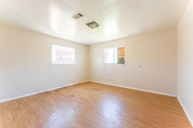 Empty room with light wood finished floors, visible vents, cooling unit, and baseboards | Image 7