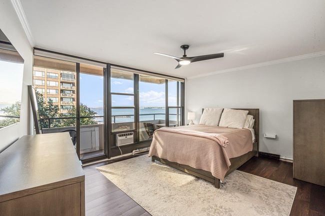 Bedroom with crown molding, a water view, access to outside, dark wood finished floors, and a ceiling fan | Image 4