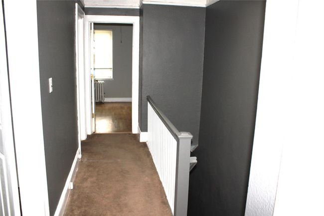 Corridor with an upstairs landing, carpet flooring, baseboards, and radiator heating unit | Image 17