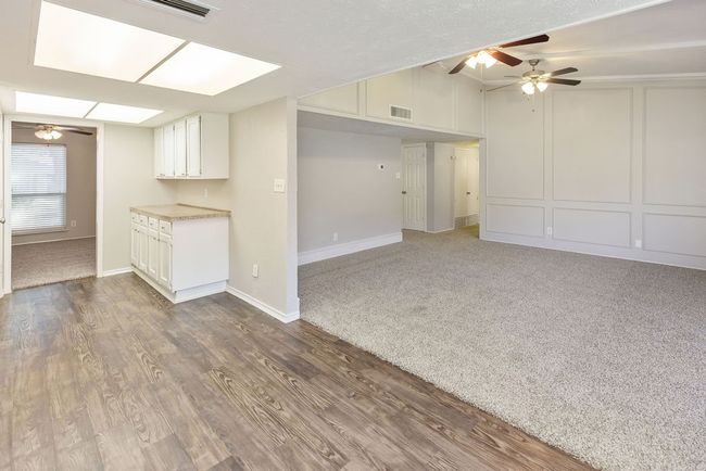 Unfurnished living room with a decorative wall, wood finished floors, and ceiling fan | Image 11