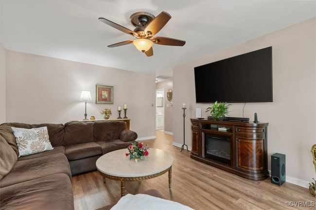 Living room with light wood finished floors, ceiling fan, and baseboards | Image 8