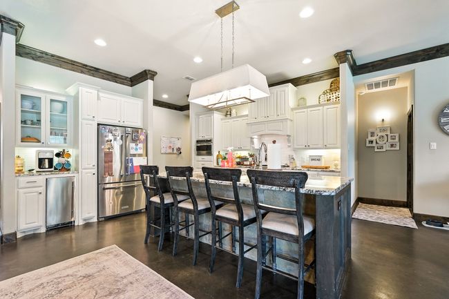 Kitchen with stainless steel appliances, concrete floors, backsplash, recessed lighting, and white cabinetry | Image 5