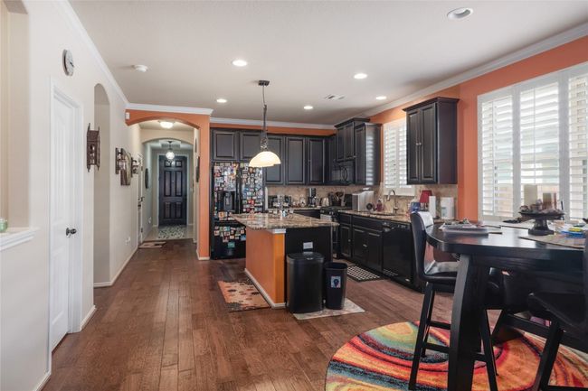 Kitchen featuring black appliances, a center island with sink, arched walkways, a sink, and backsplash | Image 9