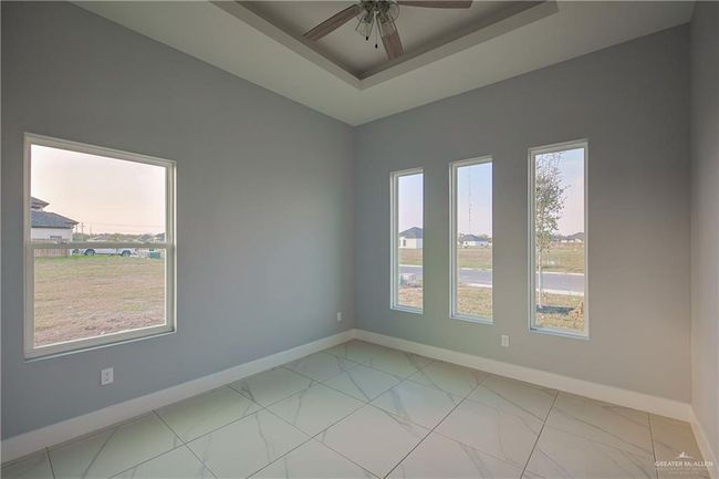 Unfurnished room featuring a wealth of natural light, ceiling fan, and a raised ceiling | Image 13