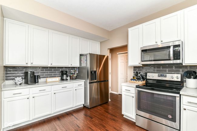 kitchen with appliances with stainless steel finishes, backsplash, and white cabinetry | Image 10