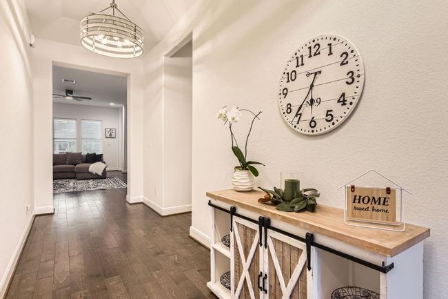 Hallway with dark wood finished floors and a chandelier | Image 5