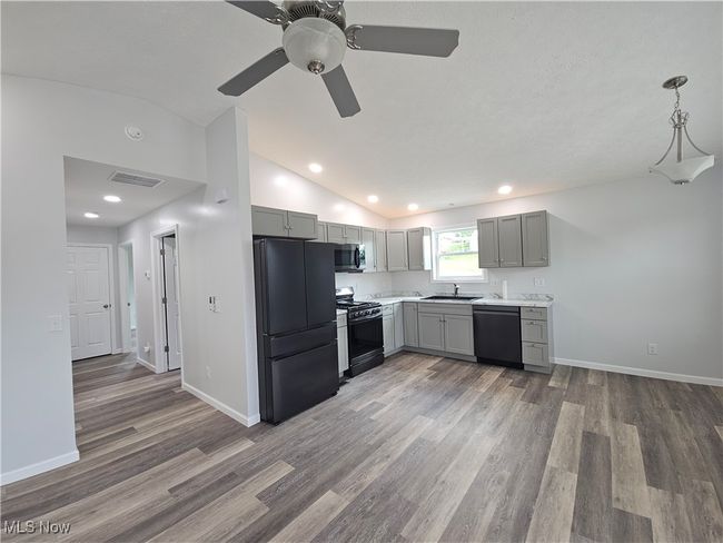 LVT flooring throughout with vaulted ceilings in living room and eat in kitchen | Image 7