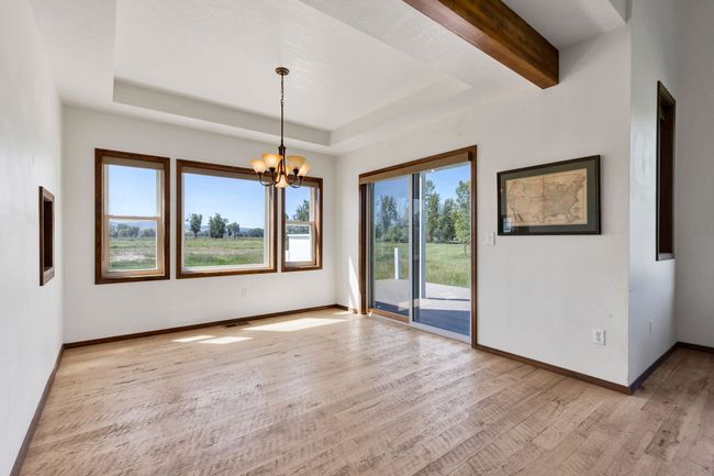Unfurnished room with light wood-style flooring, a chandelier, baseboards, and a raised ceiling | Image 18
