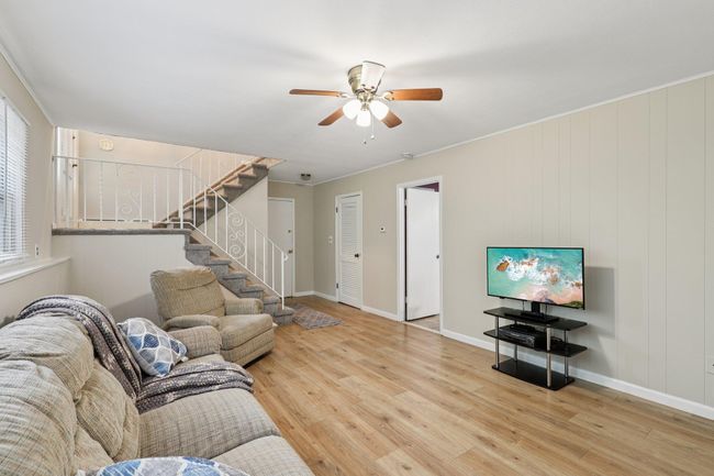 Living room with ceiling fan, wood finished floors, a brick fireplace, and built in features | Image 22