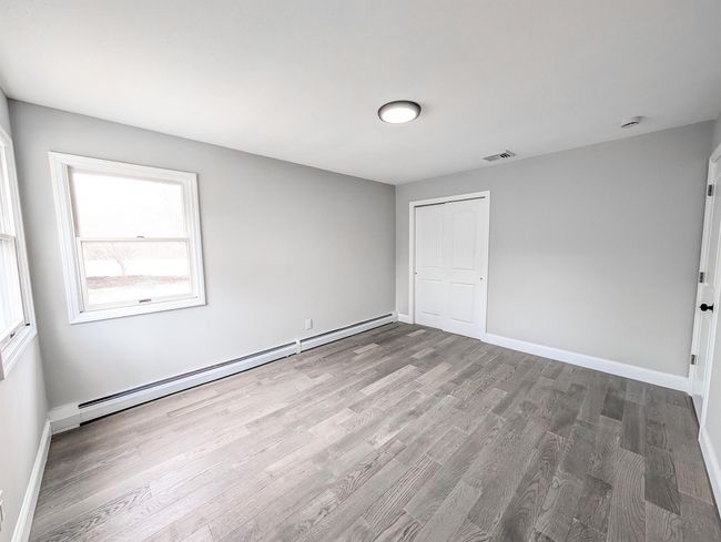 Unfurnished bedroom with baseboards, visible vents, wood finished floors, baseboard heating, and a closet | Image 11