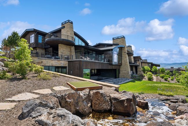 Rear view of house featuring a chimney, a balcony, and stone siding | Image 68