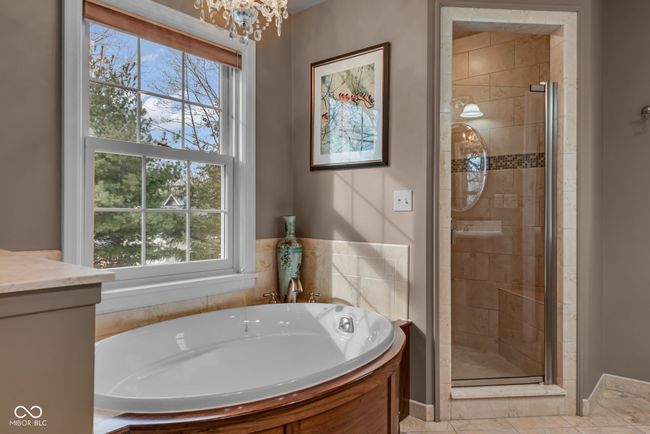 bathroom with a stall shower, a bath, and a chandelier | Image 21