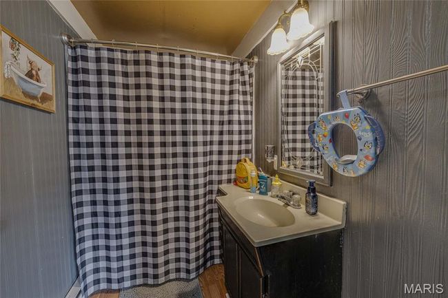 Full bathroom with a shower with shower curtain, vanity, and wallpapered walls | Image 16