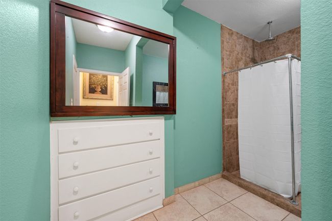 Bathroom with a tile shower, tile patterned flooring, and a textured wall | Image 17