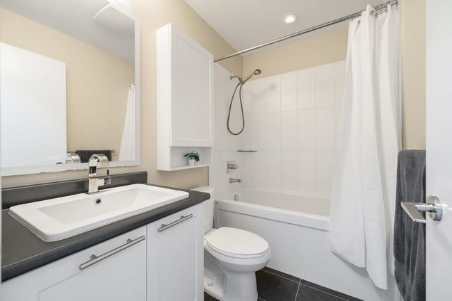 Full bath with toilet, vanity, shower / bathtub combination with curtain, and tile patterned floors | Image 14