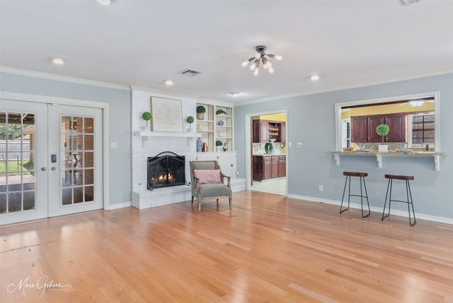 Unfurnished living room featuring a brick fireplace, french doors, light wood-style floors, and ornamental molding | Image 7