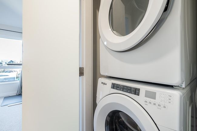 Clothes washing area featuring laundry area, carpet flooring, and stacked washing maching and dryer | Image 25