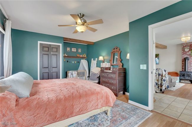 Bedroom featuring wood finished floors, a wood stove, and ceiling fan | Image 19