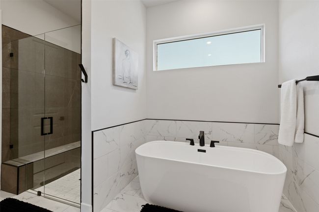 Bathroom featuring a freestanding tub, wainscoting, marble finish floor, and a stall shower | Image 19